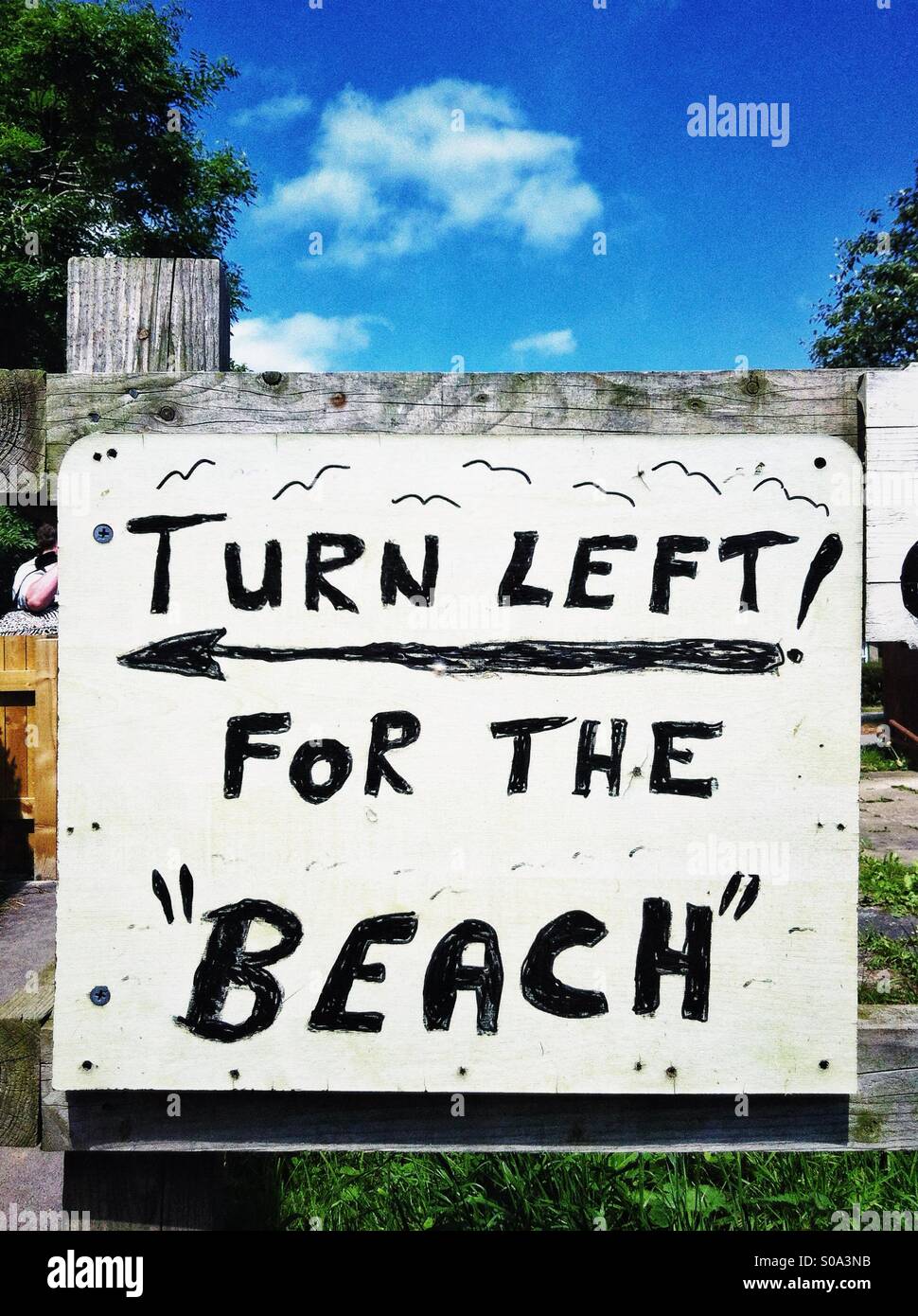 Handwritten sign reading 'Turn Left For The Beach' - Smartphone Captured Stock Image