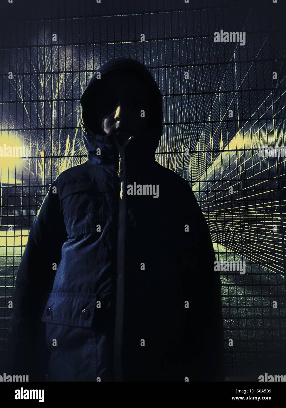 Boy in raincoat outdoors at night - Smartphone Captured Stock Image