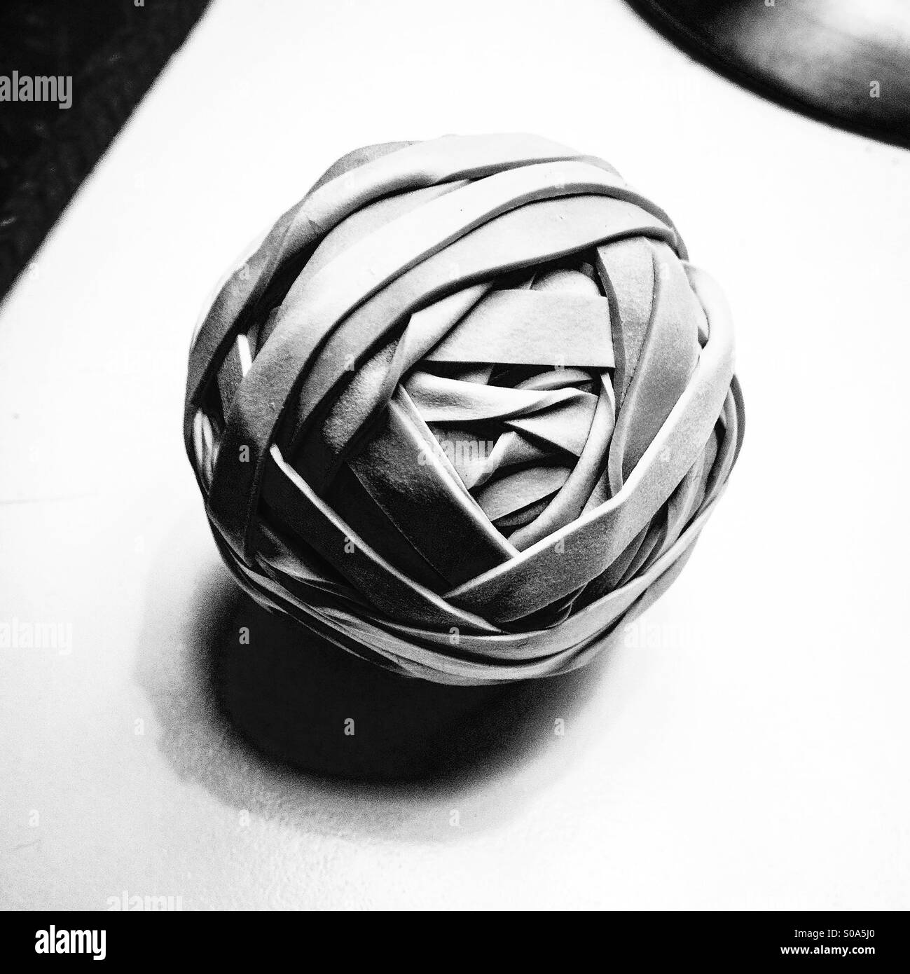 Rubber band ball resting on a desk in black and white Stock Photo