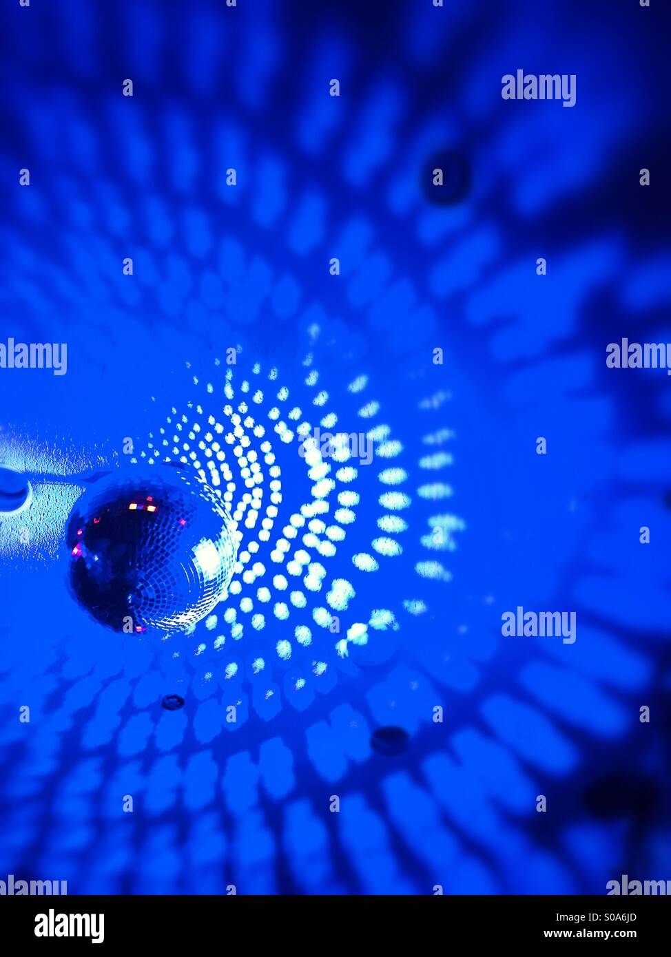 Blurred semi abstract mirrored blue disco ball and surrounding area Stock Photo