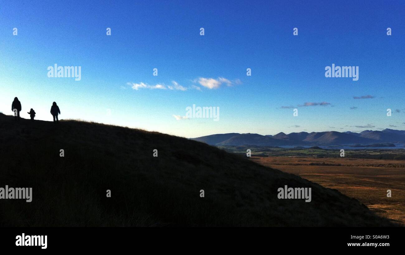 Silhouette of 2 adults and a child walking in hills. - Smartphone Captured Stock Image