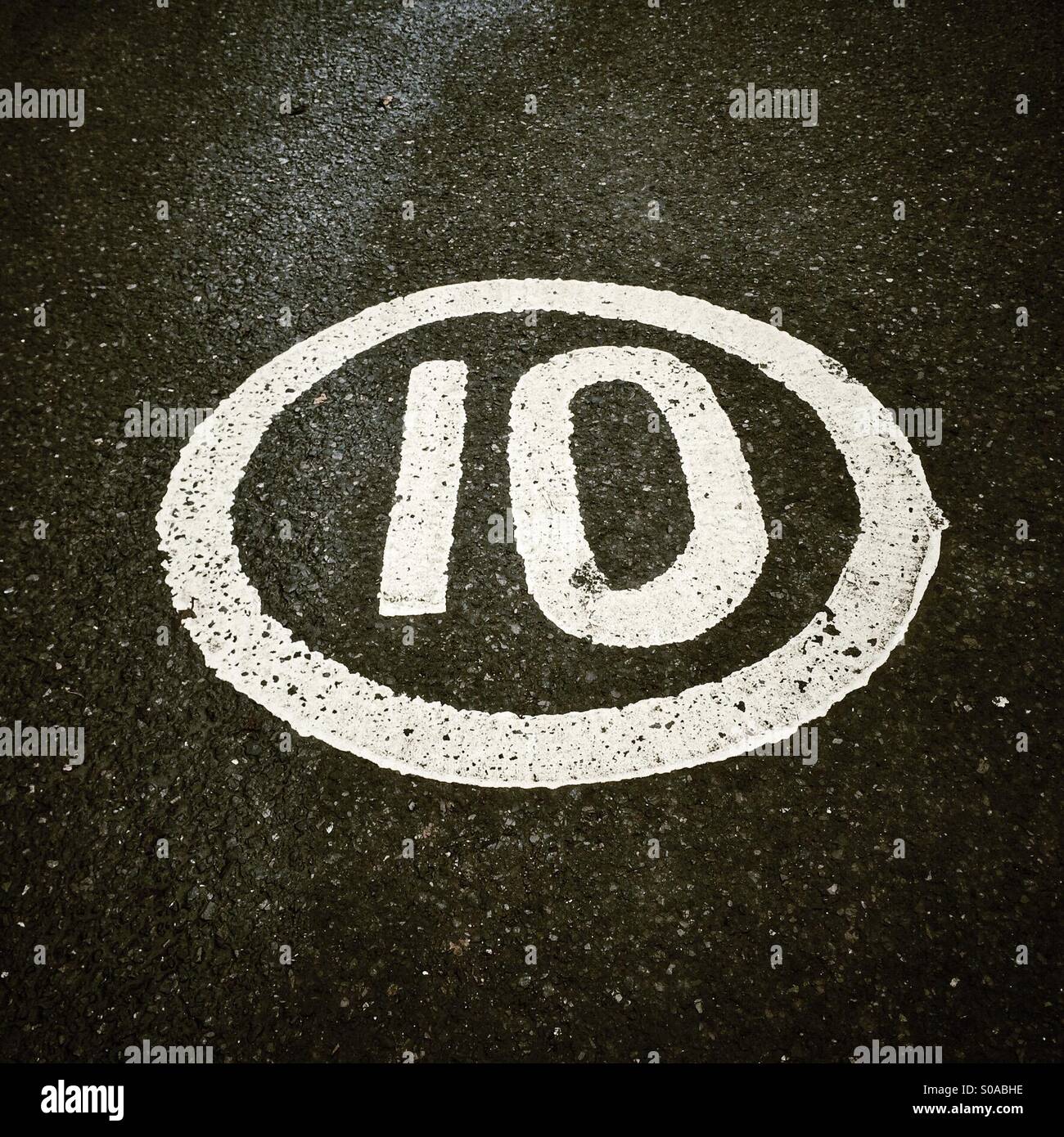 Ten mile an hour speed limit painted on road Stock Photo