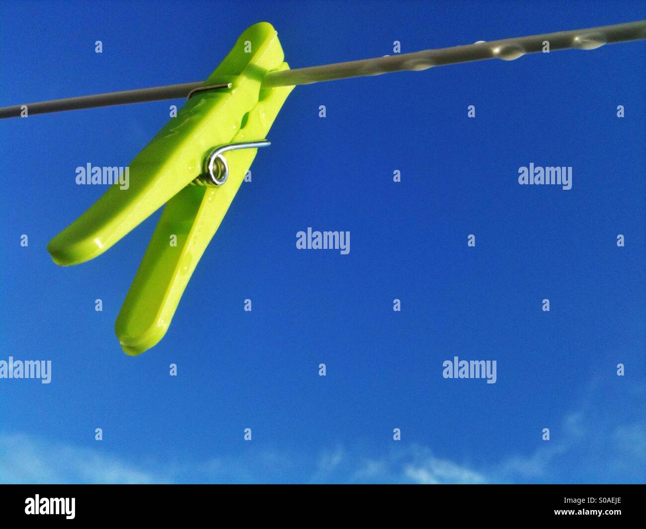 Yellow peg on washing line against blue sky. - Smartphone Captured Stock Image