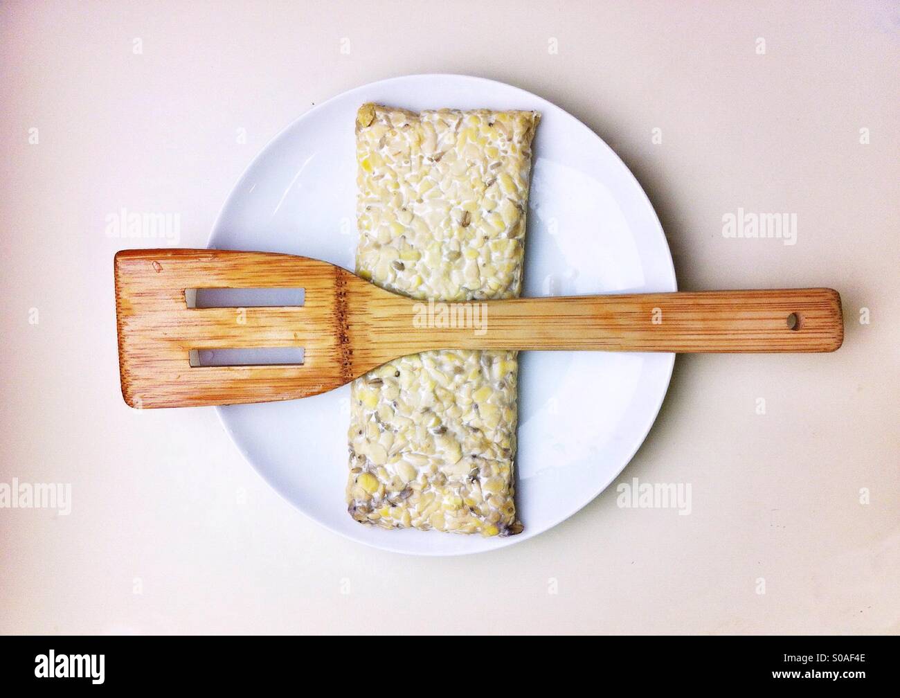 Block of tempeh on a plate with bamboo spatula - Smartphone Captured Stock Image