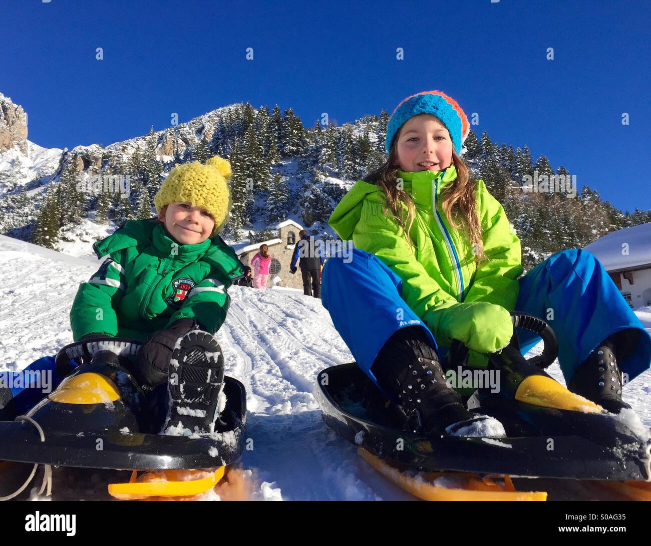 Sledging siblings having fun on a beautiful winter day - Smartphone Captured Stock Image