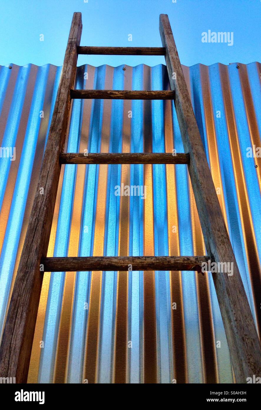 Wooden ladder against a metal wall - Smartphone Captured Stock Image