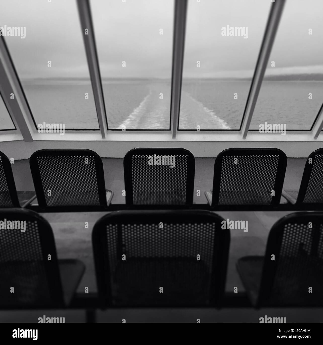 Empty seats on an ocean going ferry with the wake of the ship in the background. - Smartphone Captured Stock Image