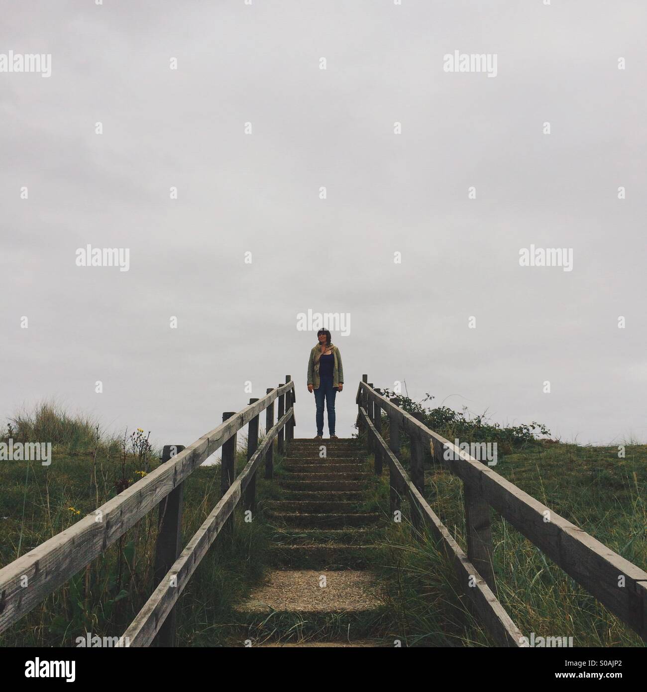Person standing at the top of some steps outside. Stock Photo