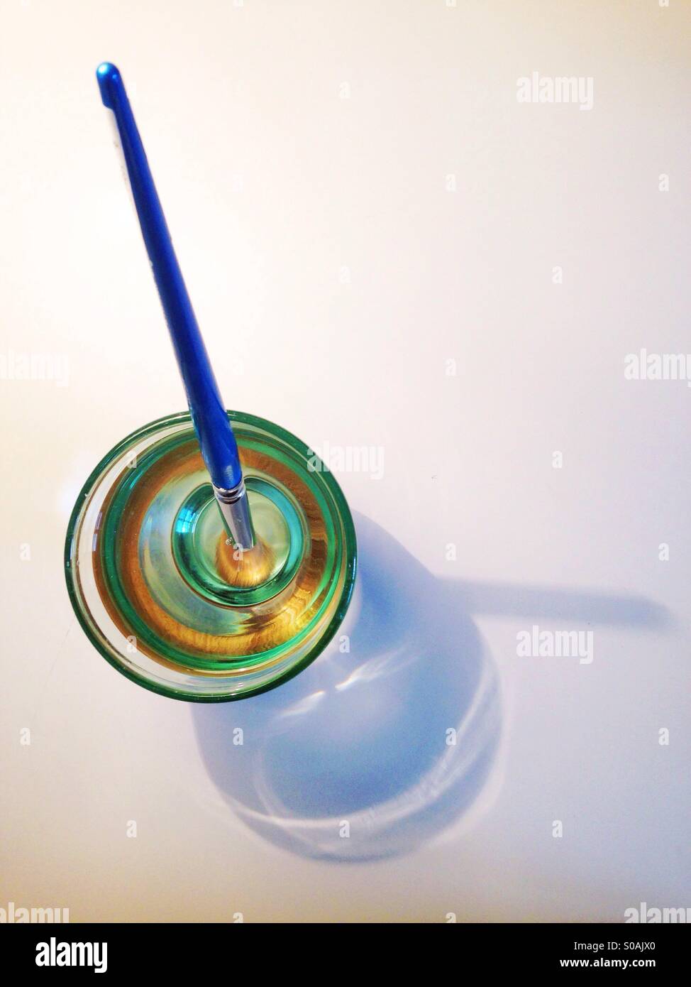 Paint brush in water on white table Stock Photo Alamy