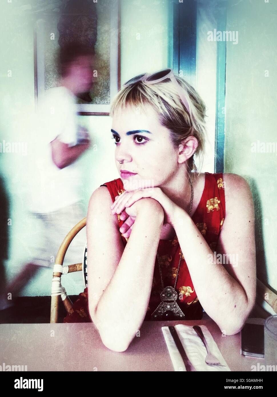 Young blonde woman daydreaming in the restaurant - Smartphone Captured Stock Image