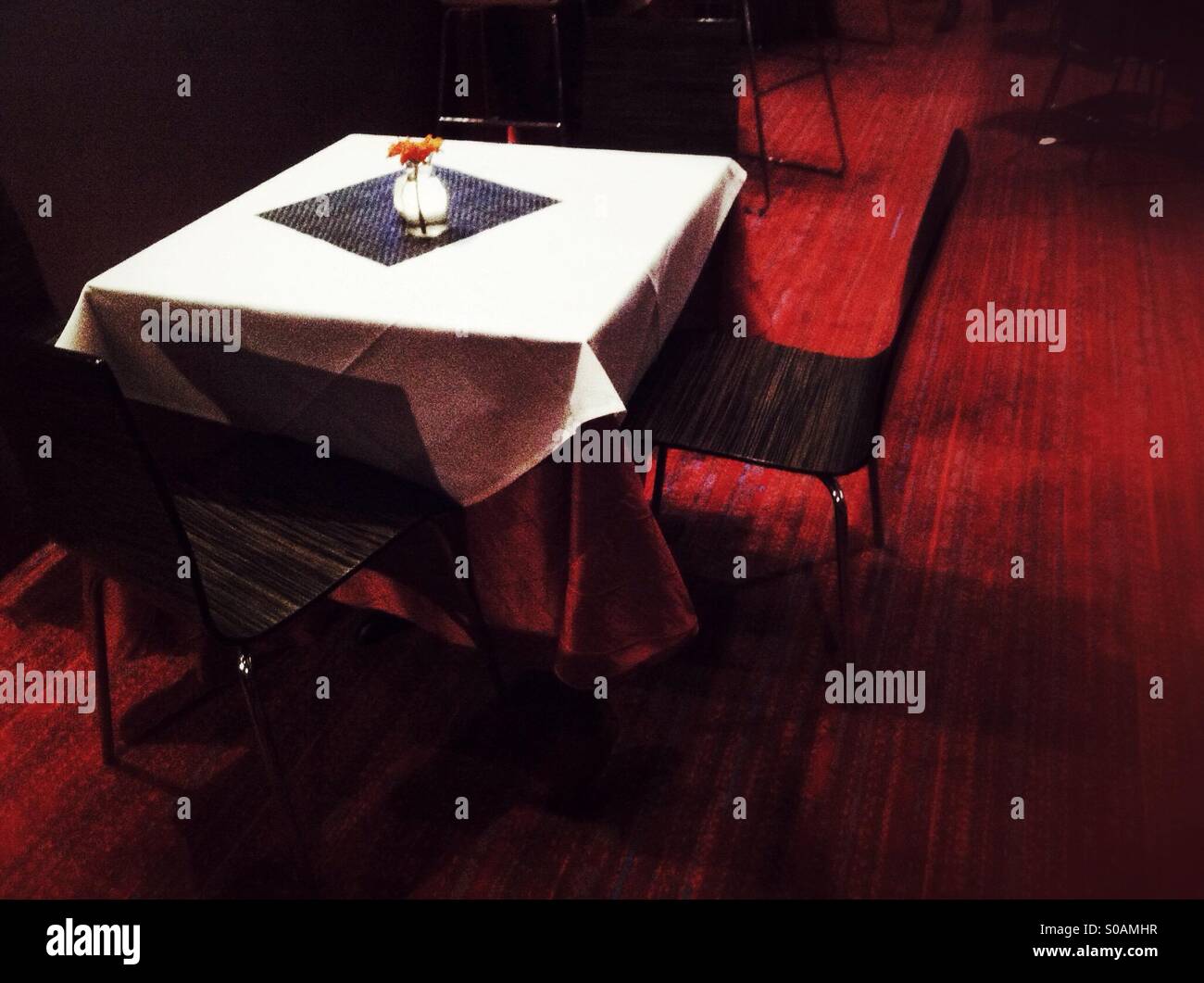 Empty table with white tablecloth and a flower in a vase in a restaurant - Smartphone Captured Stock Image