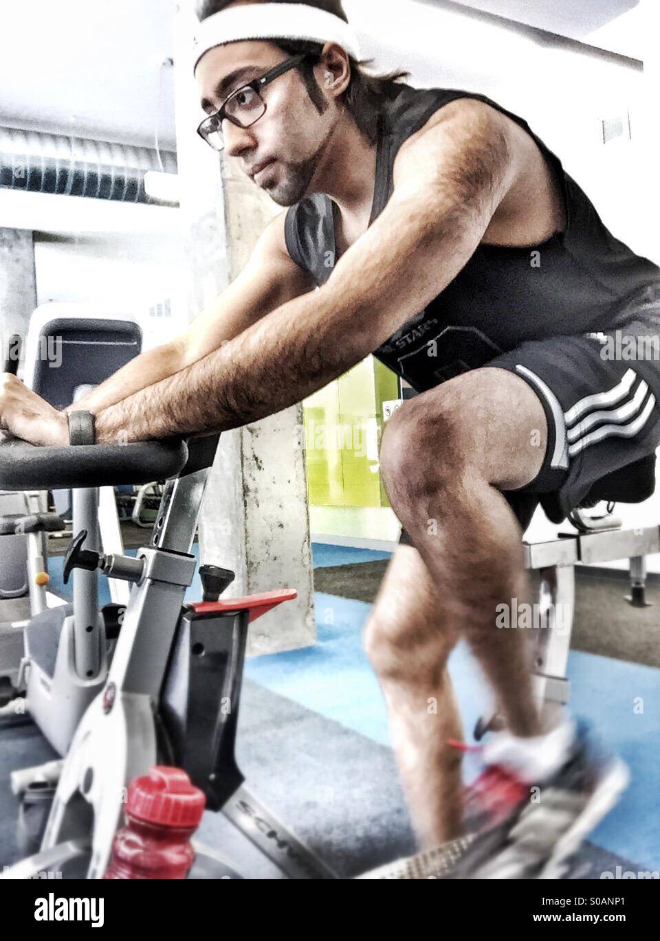A guy at the gym on a stationary bike Stock Photo
