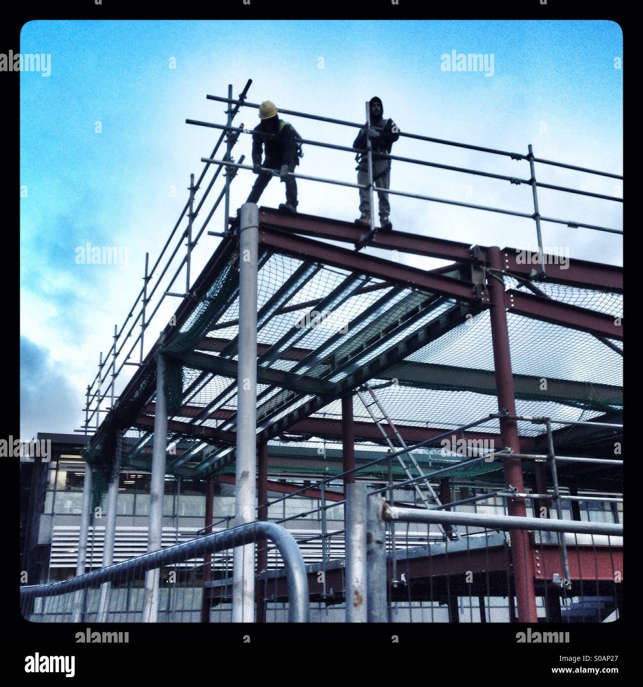 Builders putting up a scaffolding around a steel frame - Smartphone Captured Stock Image