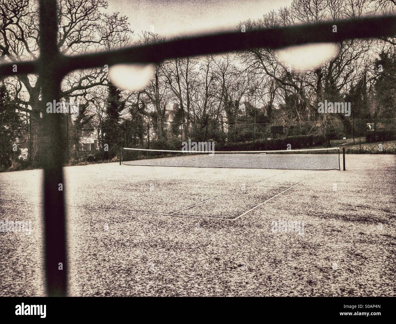 Snow covered tennis court seen through mesh fence Stock Photo Alamy