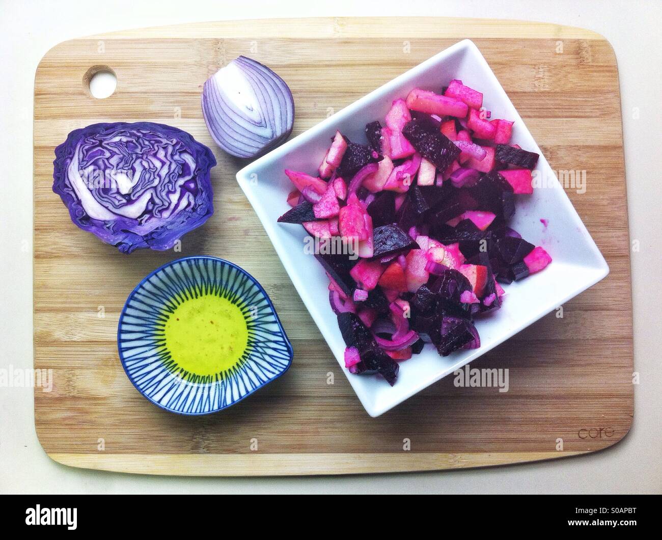 Russian style beet salad on a cutting board with red cub age, onion and olive oil Stock Photo