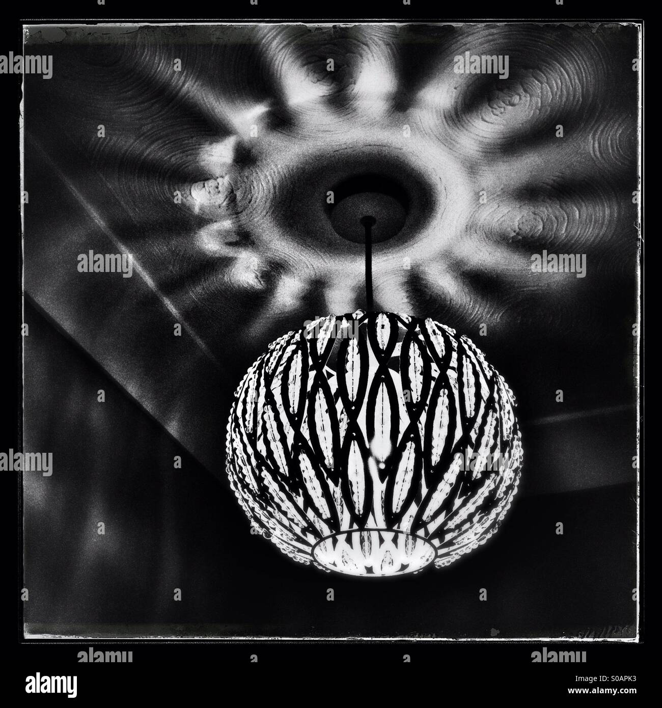 Domestic light fitting throwing an intense circular shadow on the ceiling. - Smartphone Captured Stock Image