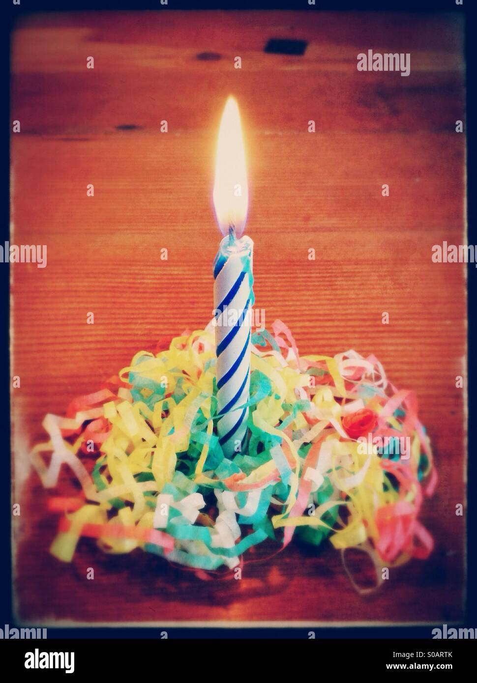 Party candle on a wood table, with streamers Stock Photo Alamy