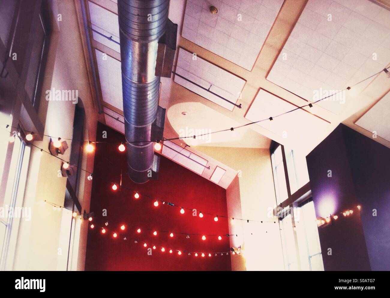 strings of lights adorning industrial style ceiling in an urban cafe Stock Photo