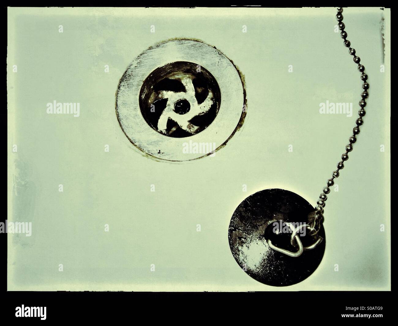 Close up of a bathroom sink, plug with chain and plug hole Stock Photo