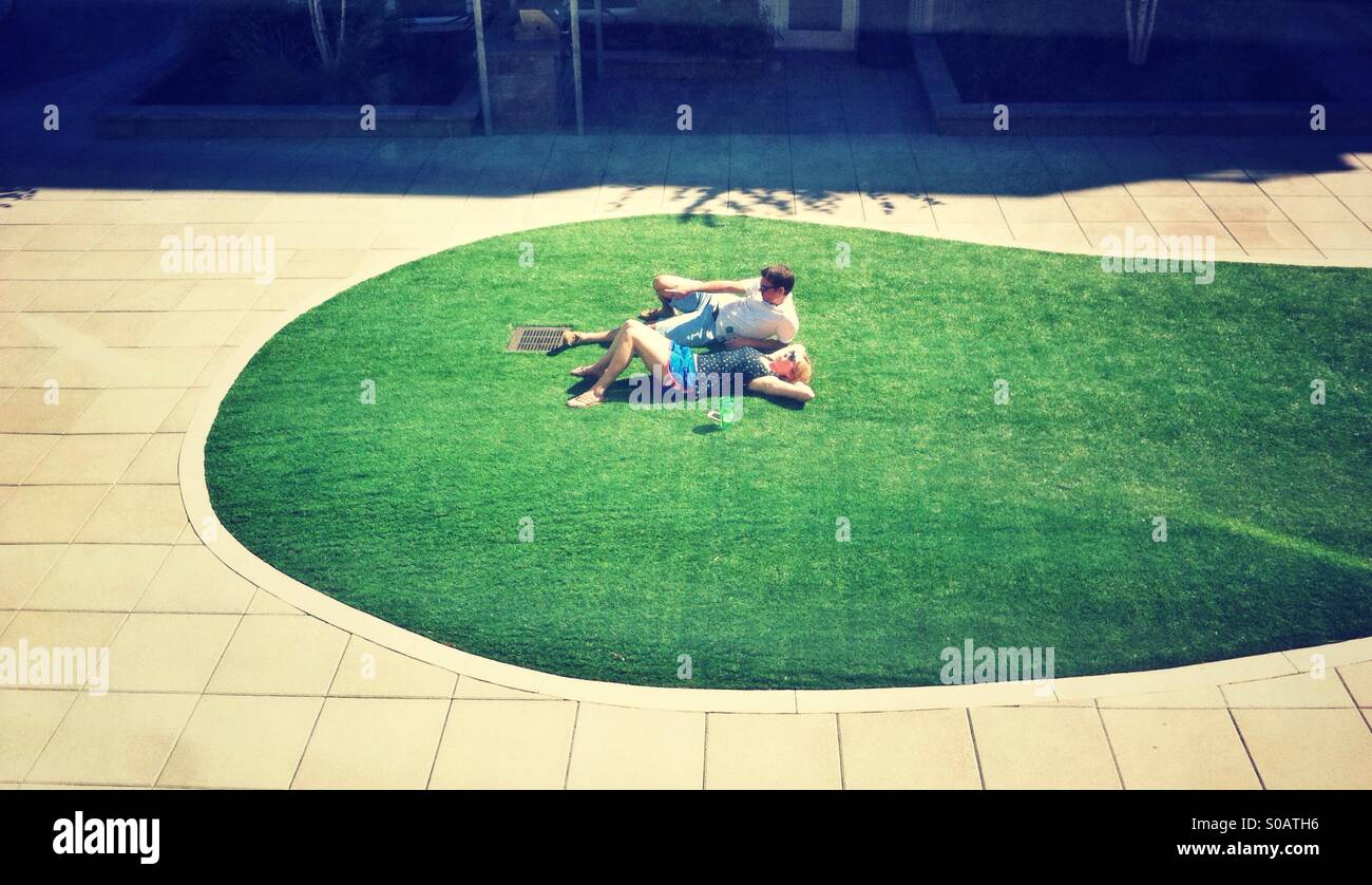 Couple sunbathing on artificial lawn - Smartphone Captured Stock Image