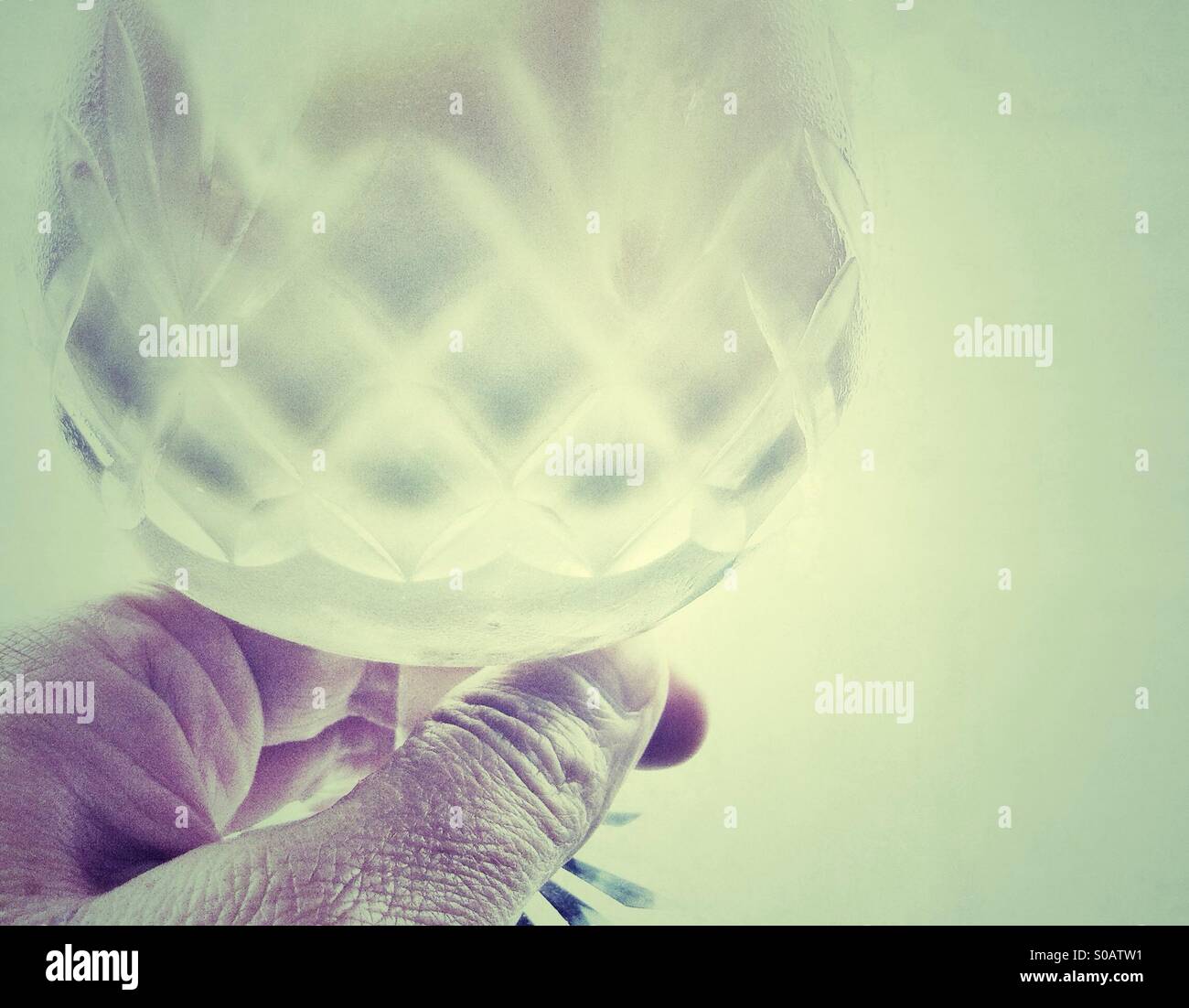 Hand holding a diamond cut stem glass - Smartphone Captured Stock Image