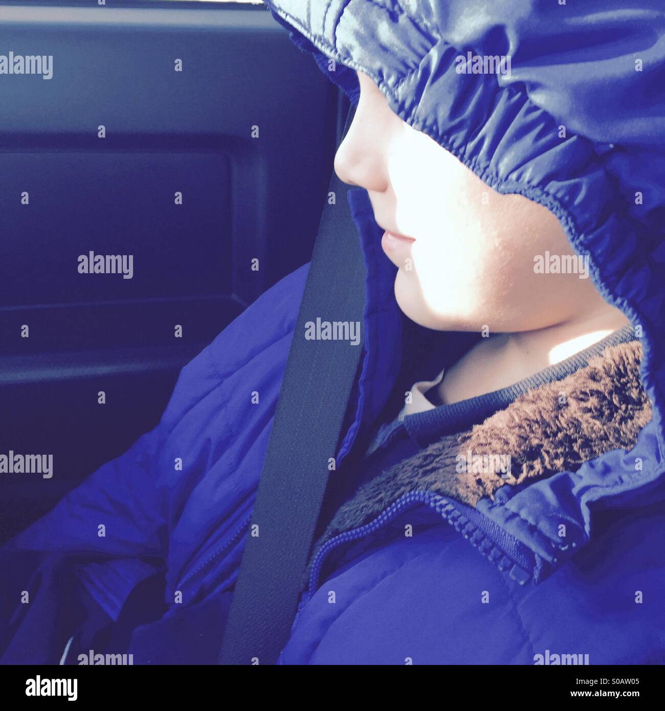 Profile of young boys face partially obscured by jacket hood Stock Photo