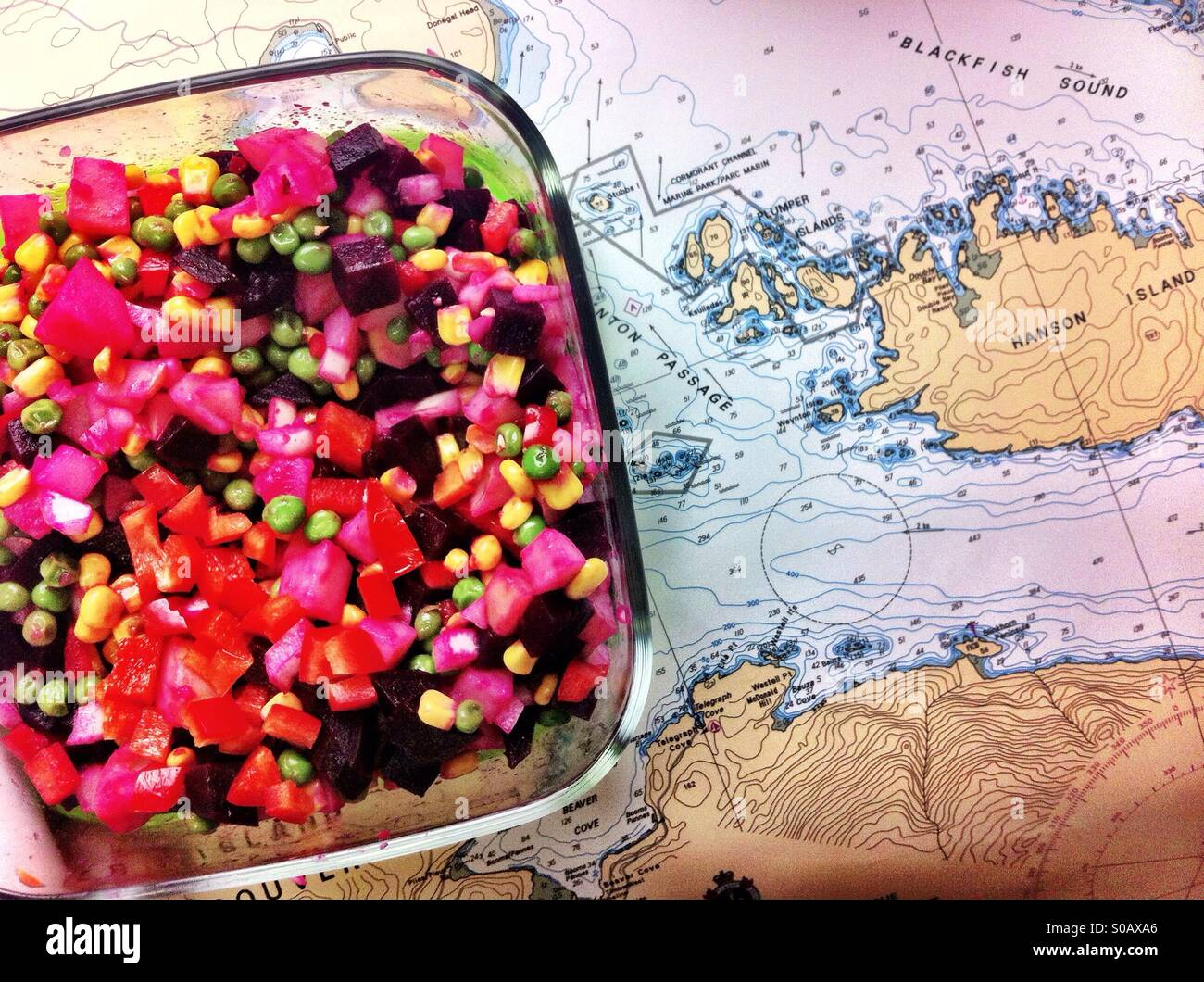 Vegetable beet salad in glass container on nautical charts - Smartphone Captured Stock Image