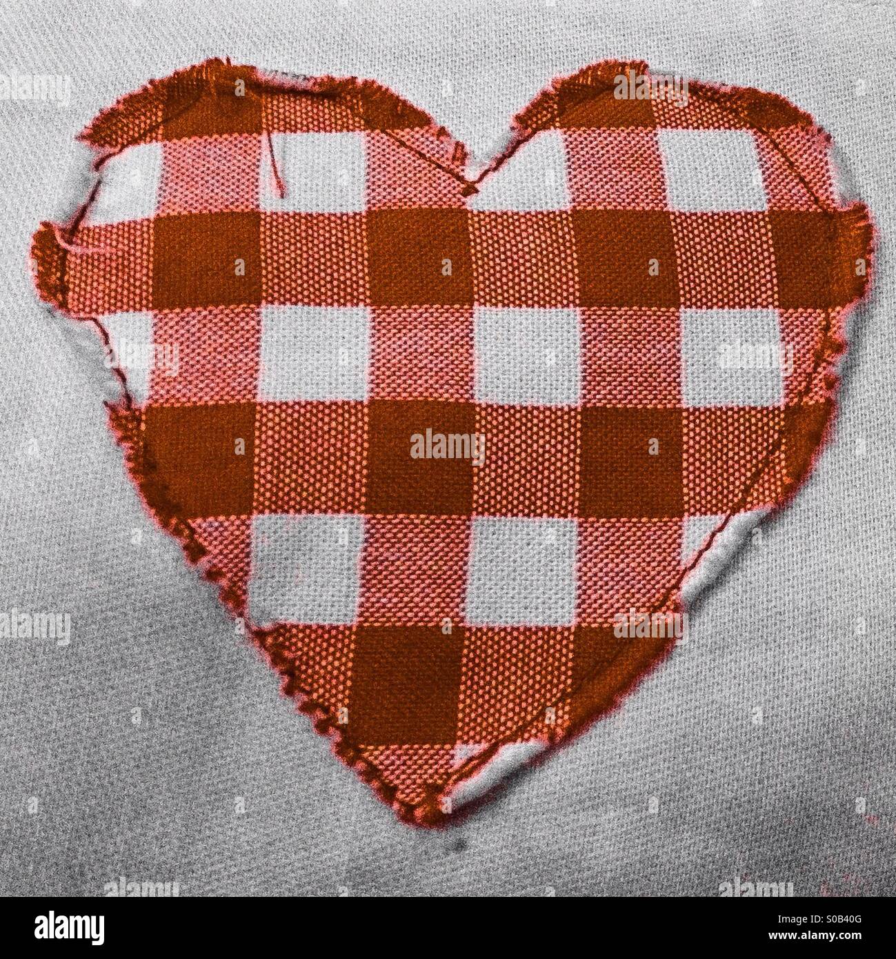 Red and white checkered heart cut out and sewn onto fabric Stock Photo