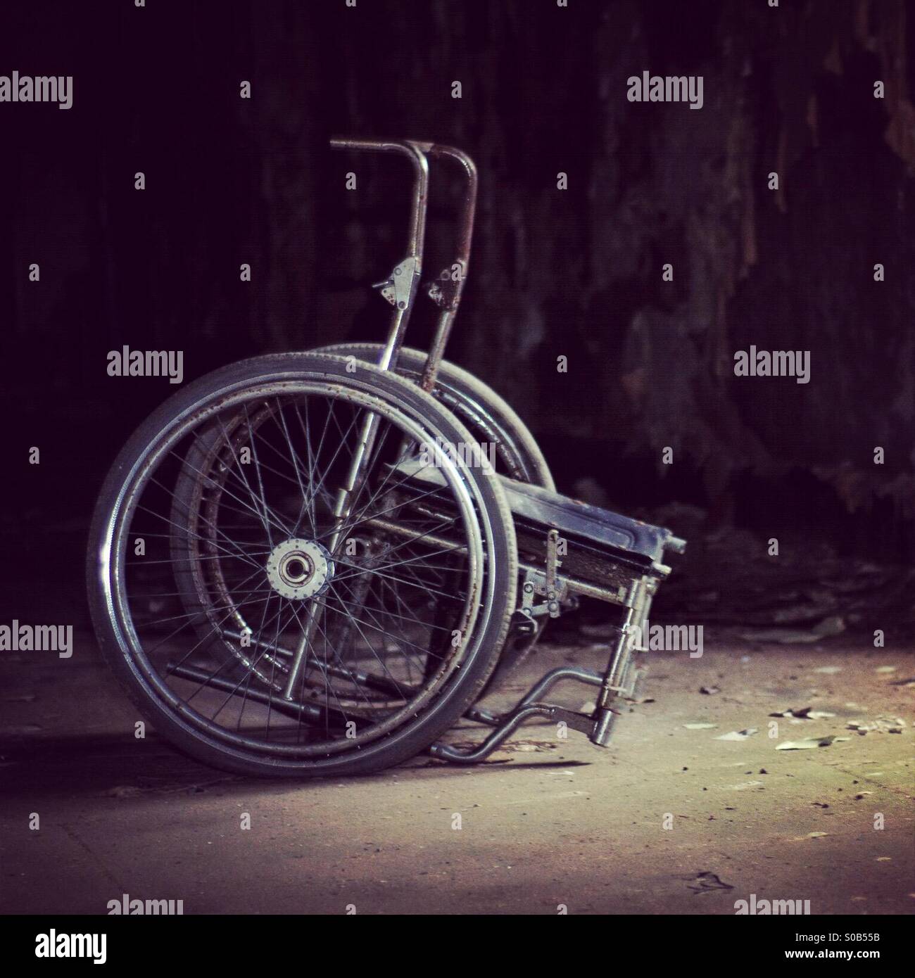 Eerie wheelchair in abandoned building Stock Photo