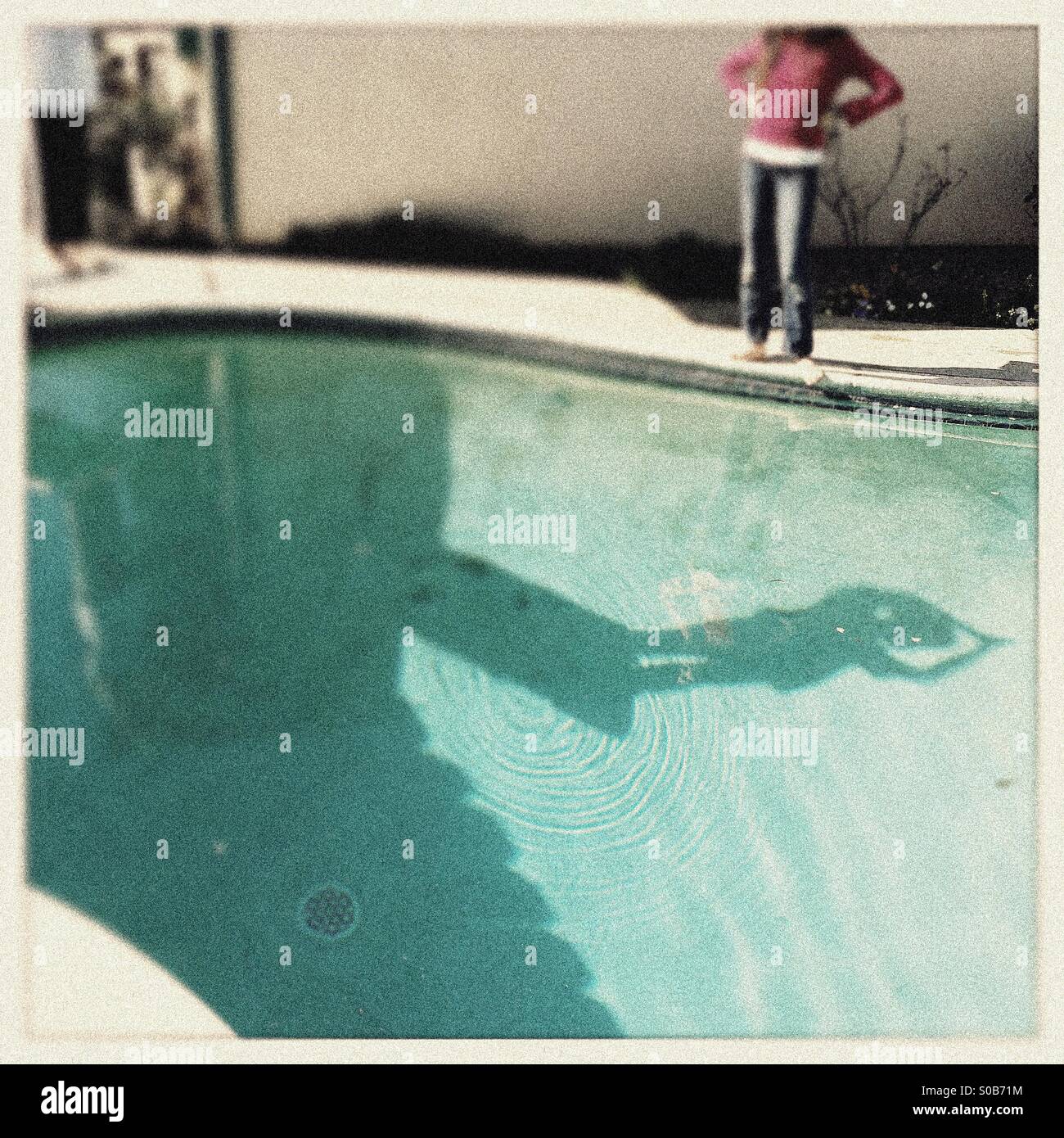 A shadow on the bottom of a swimming pool of a person diving off of a diving board. - Smartphone Captured Stock Image