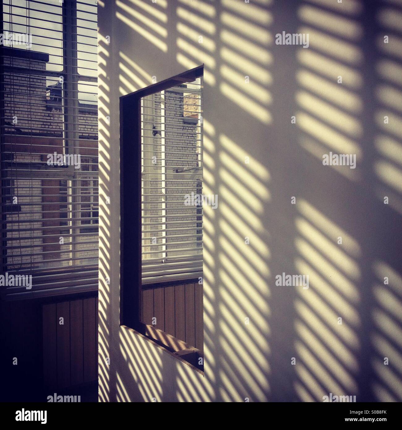 Shadows and sunlight creating lines on a white wall. Stock Photo