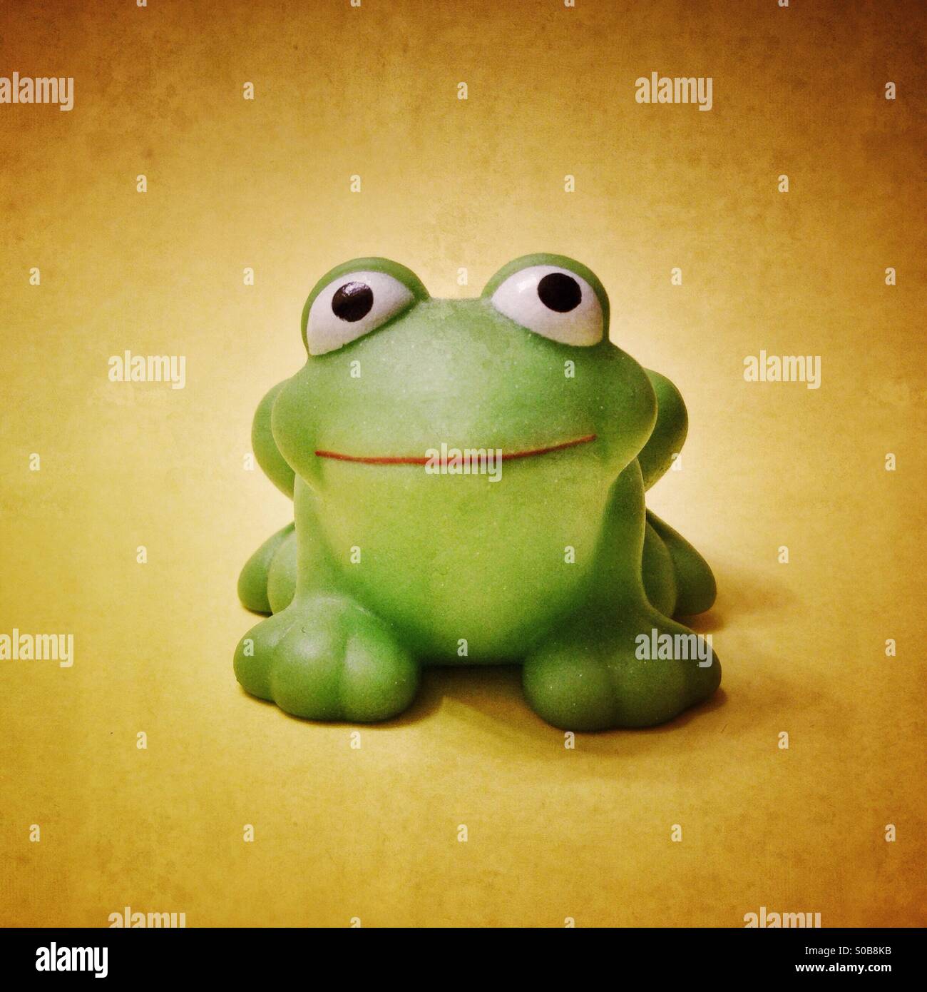Squeaky rubber frog toy on a yellow background. - Smartphone Captured Stock Image