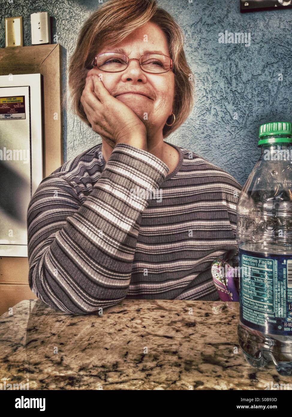 A smile from a tired lady sitting at a table. - Smartphone Captured Stock Image