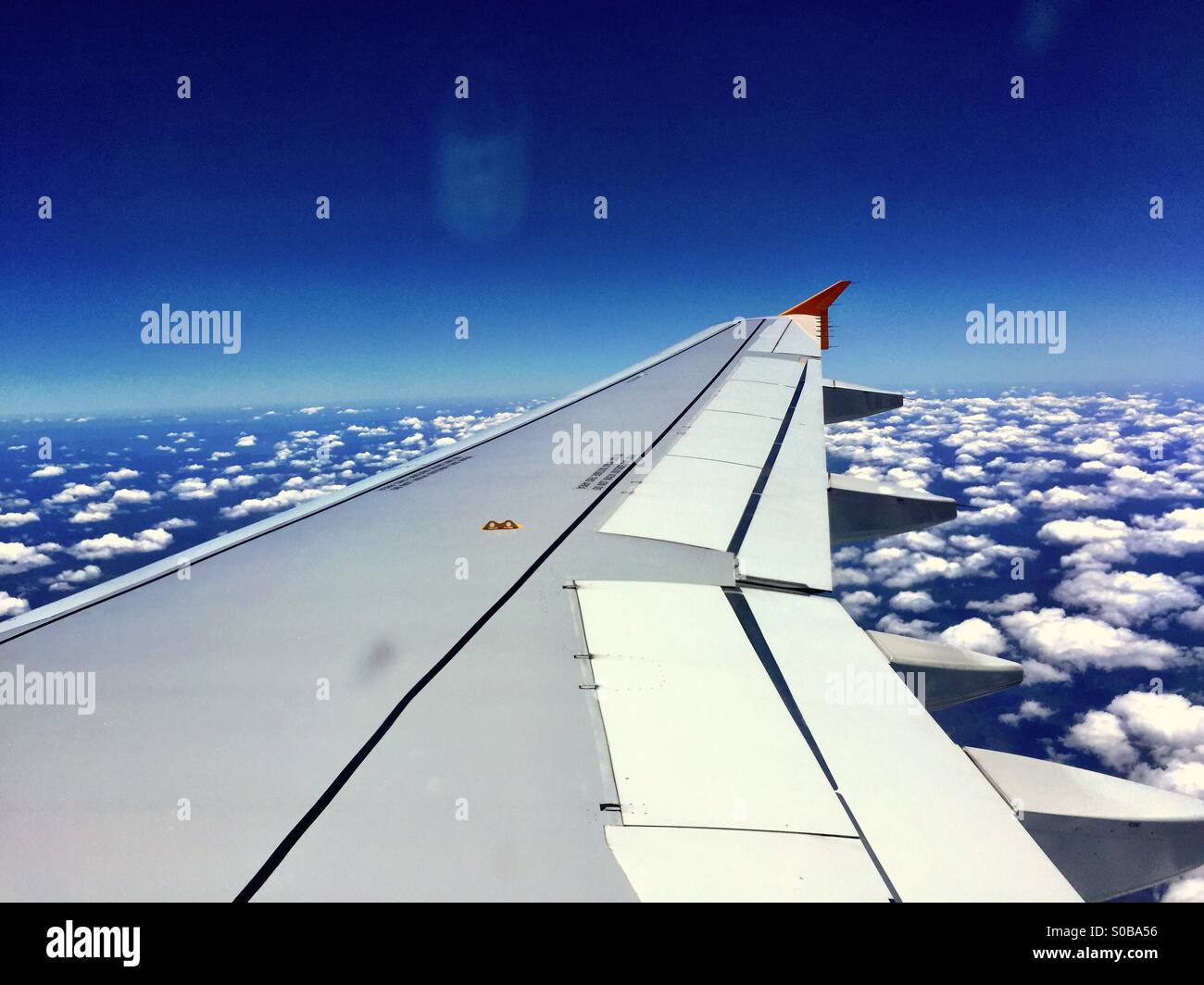 An airliner wing over an interesting cloud pattern Stock Photo