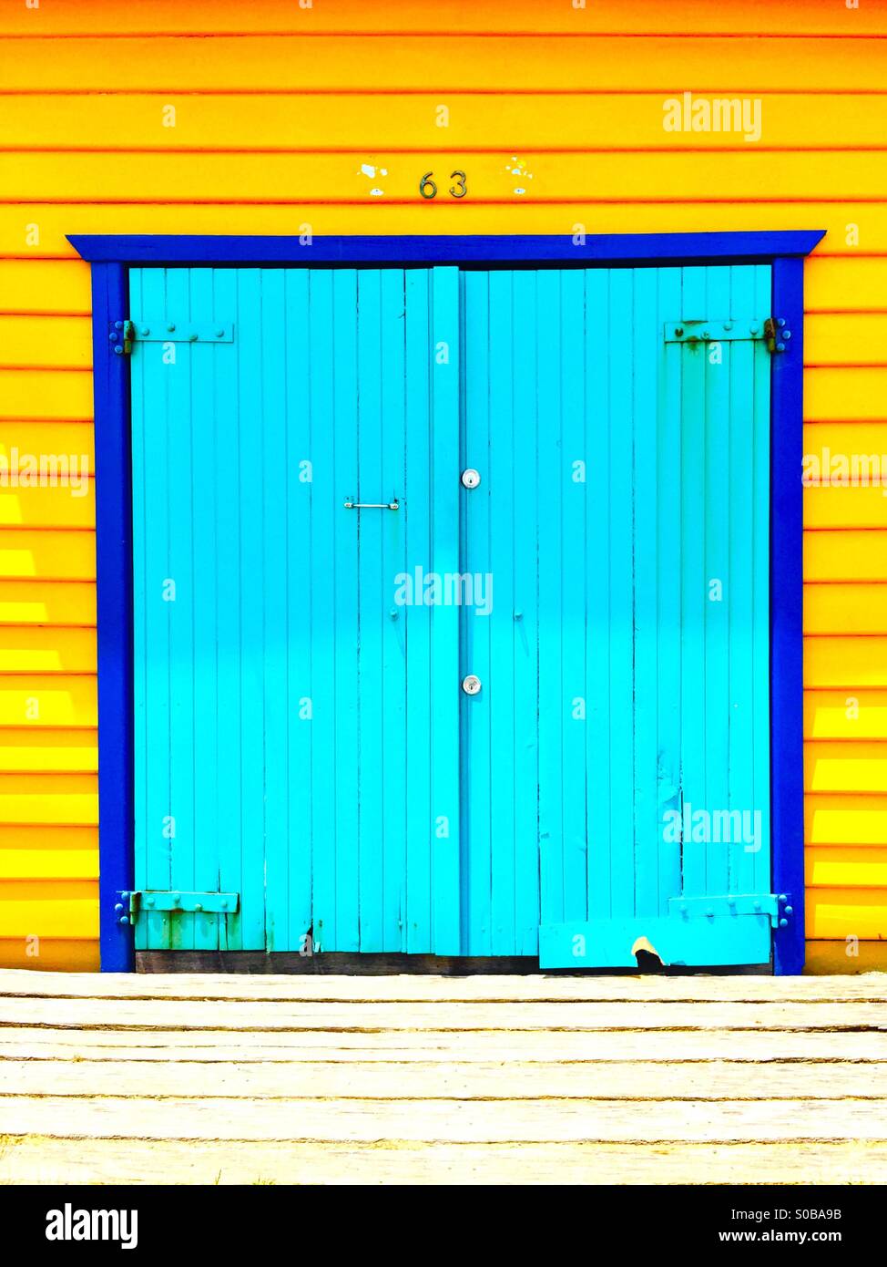 A blue door on a yellow beach house - Smartphone Captured Stock Image