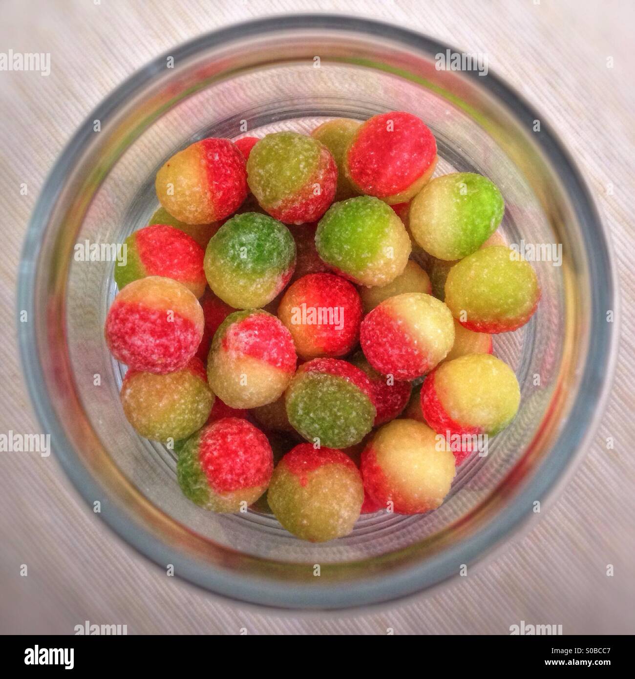 Looking down into a sweet jar filled with rosy apple sweets. Stock Photo
