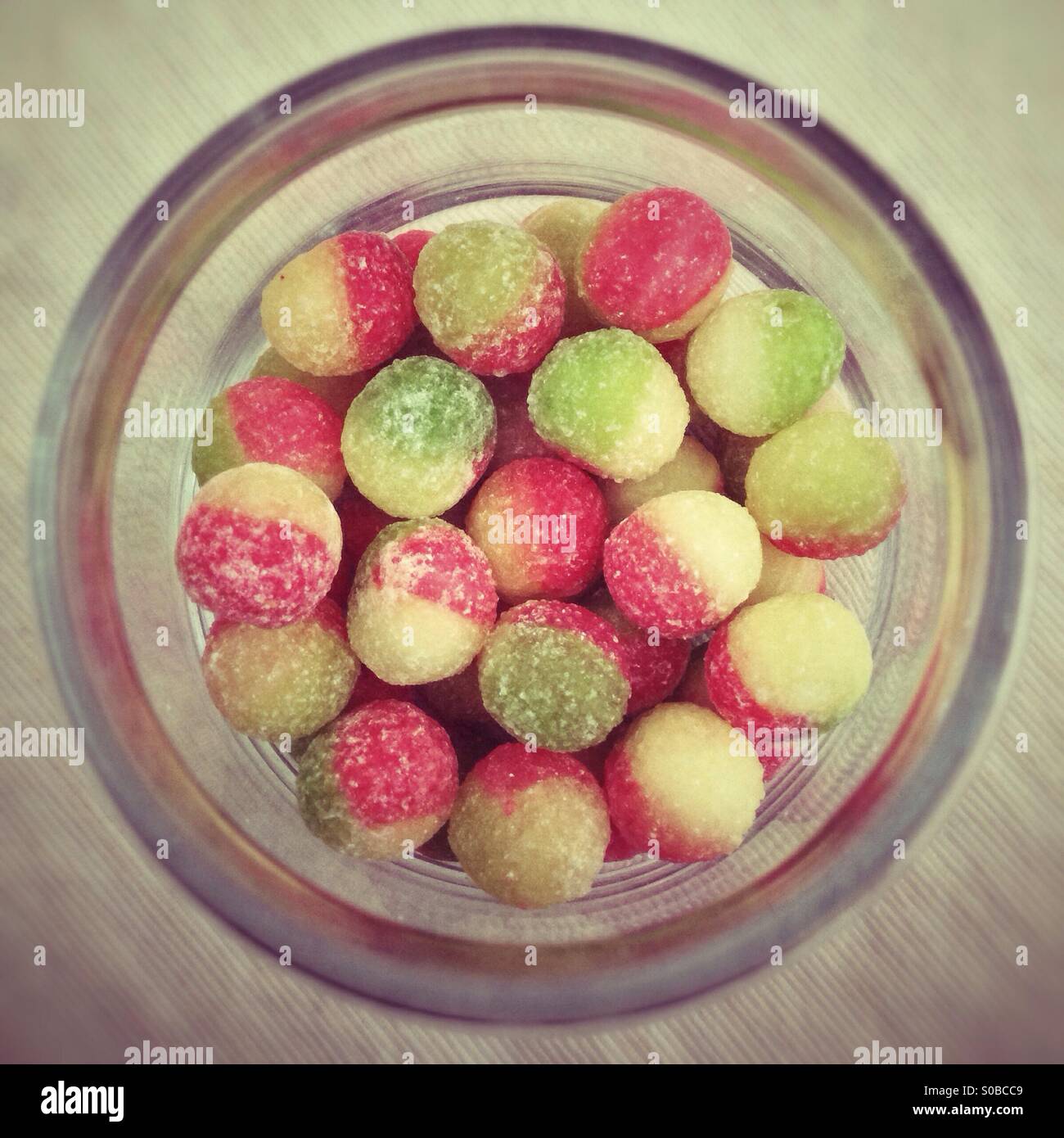 Looking down into a jar of rosy apple hard-boiled sweets. Stock Photo