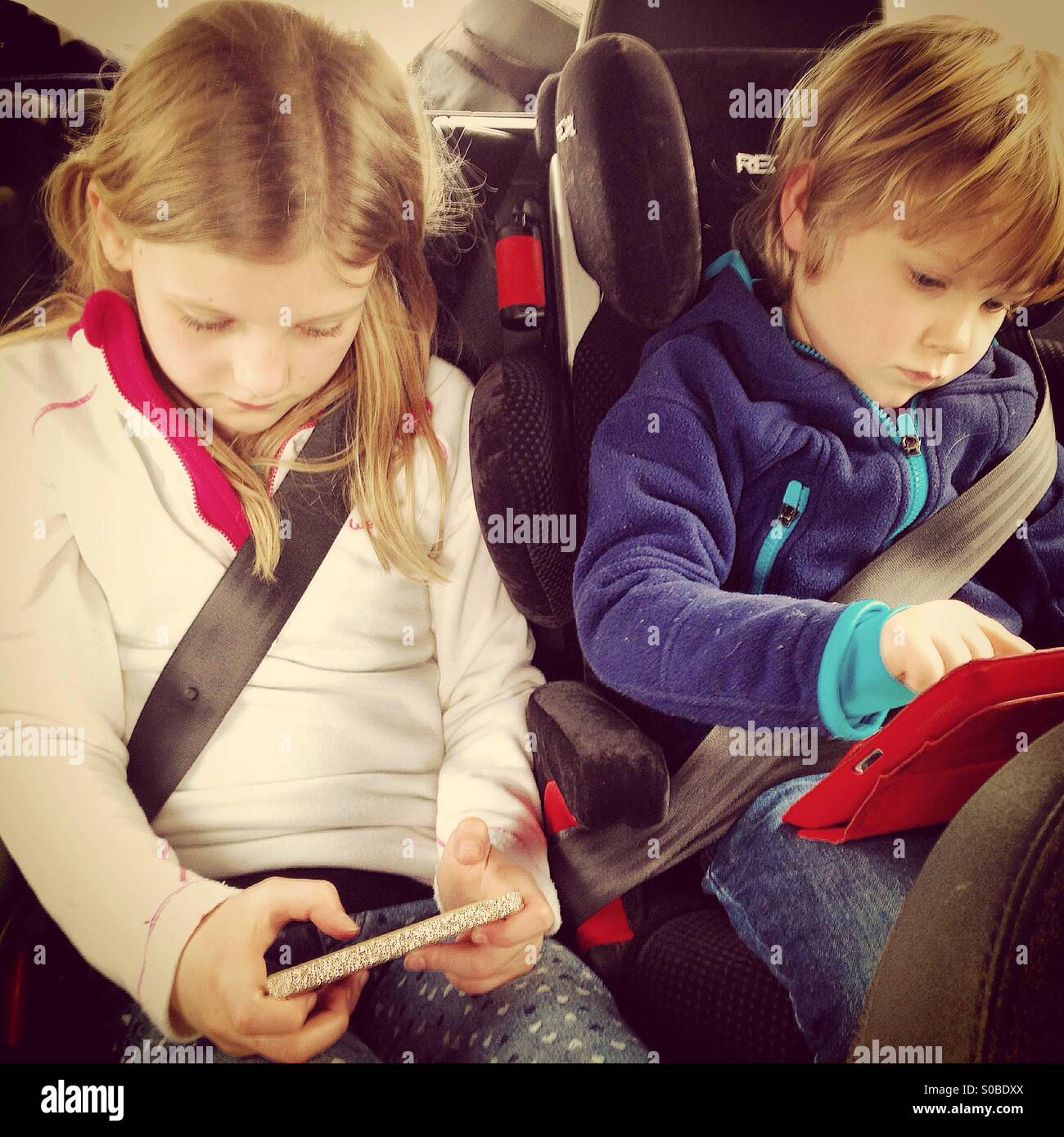 Kids playing on Screens in a Car Stock Photo