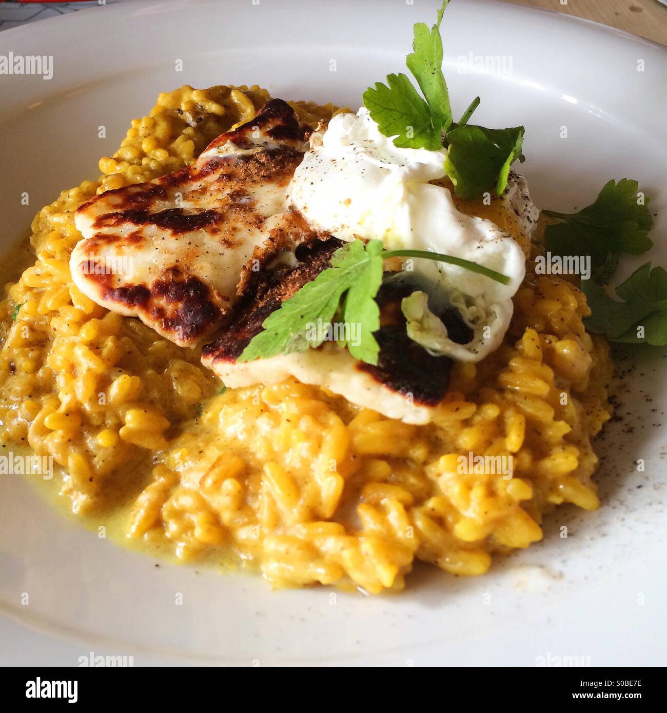 Veggie kedgeree - Grilled halloumi on turmeric rice with spinach and poached egg - Smartphone Captured Stock Image