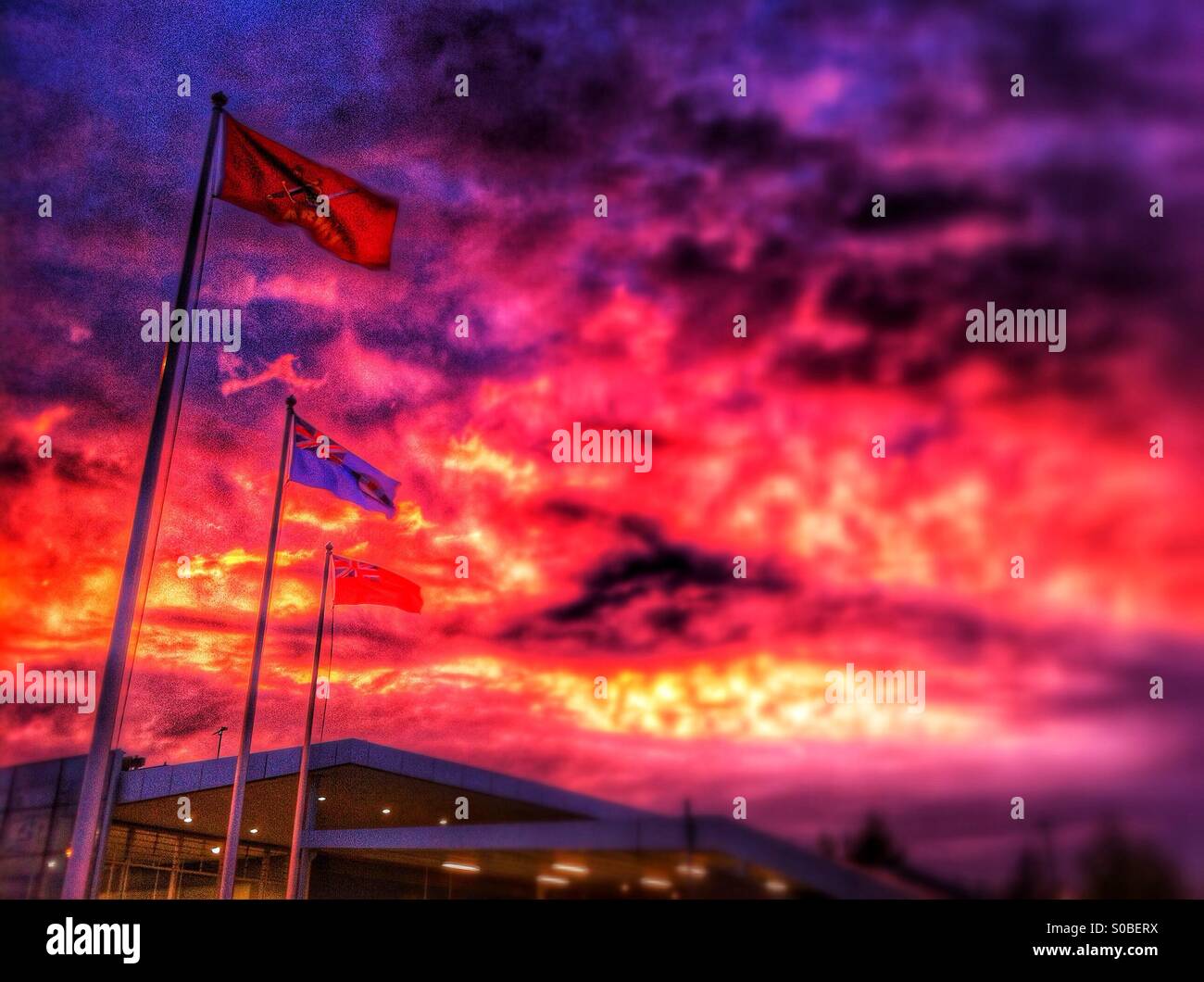A red sunset behind the flags outside the station at Ebbsfleet Kent. - Smartphone Captured Stock Image