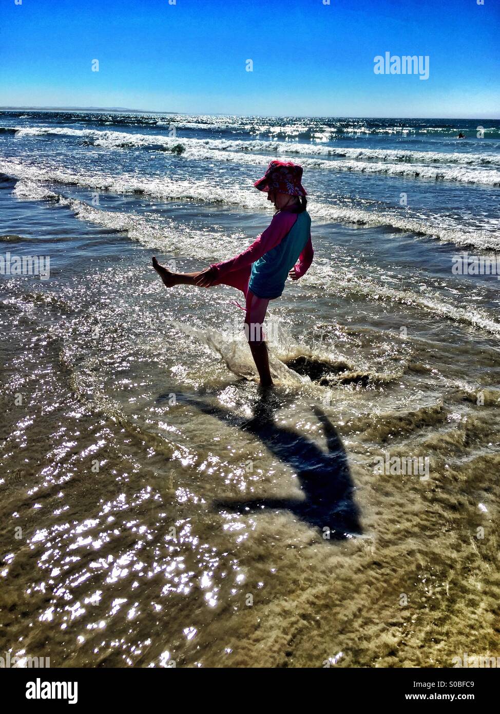Girl splashing in shallows at the beach Stock Photo