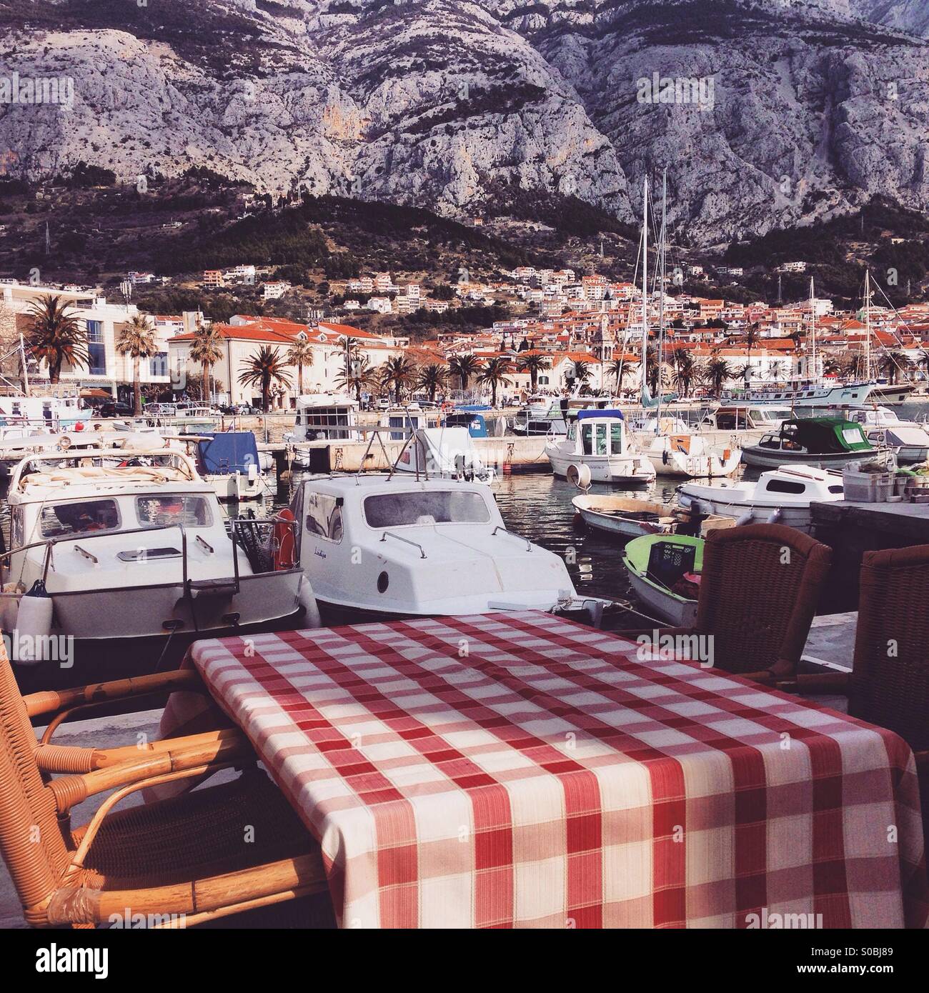 Restaurant table in marina with city Makarska and mountain in background Stock Photo