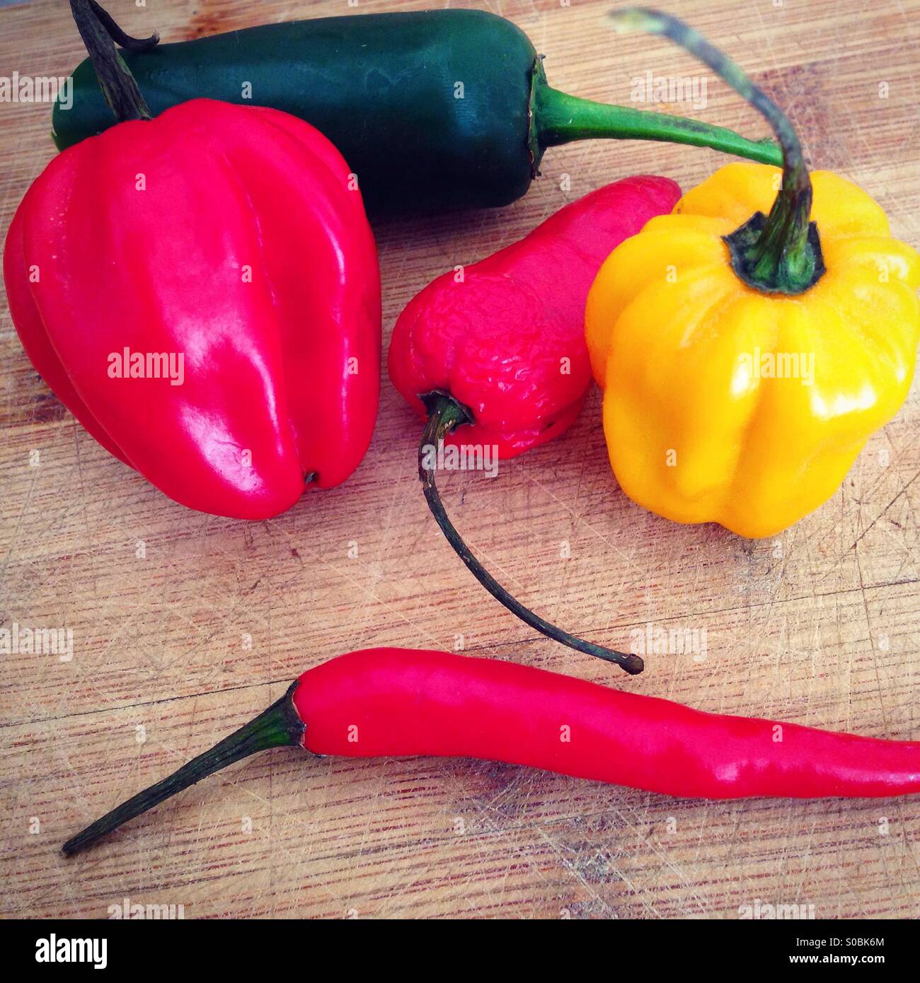 Colorful chili peppers on wooden board Stock Photo