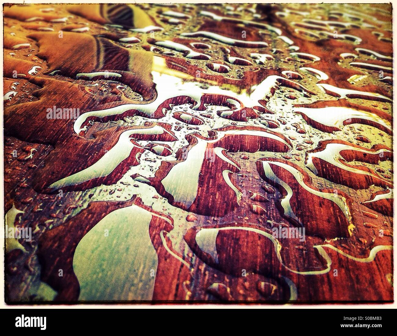 Water drops on a wooden table after raining that seems a jigsaw puzzle pieces - Smartphone Captured Stock Image