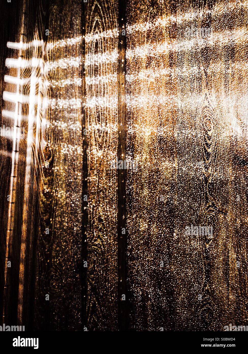 Wood grain accentuated by streaks of light shimmering through a Venetian blind. - Smartphone Captured Stock Image
