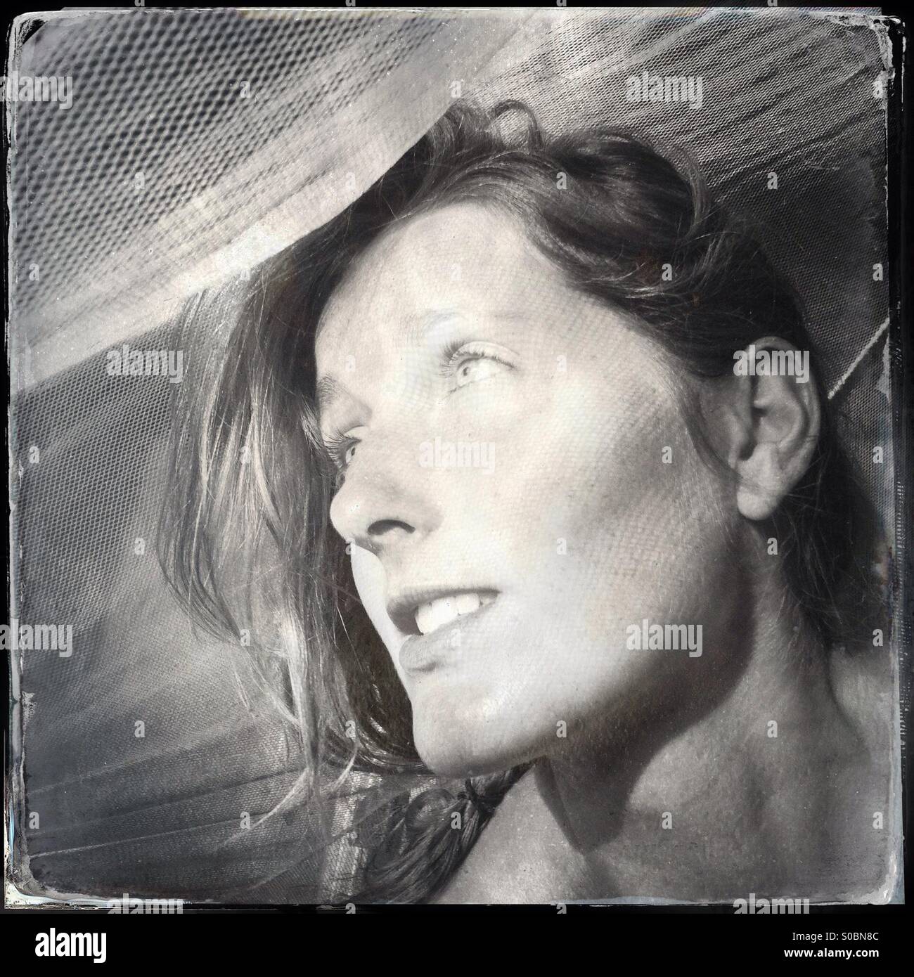 Woman looking out from under mosquito net - Smartphone Captured Stock Image