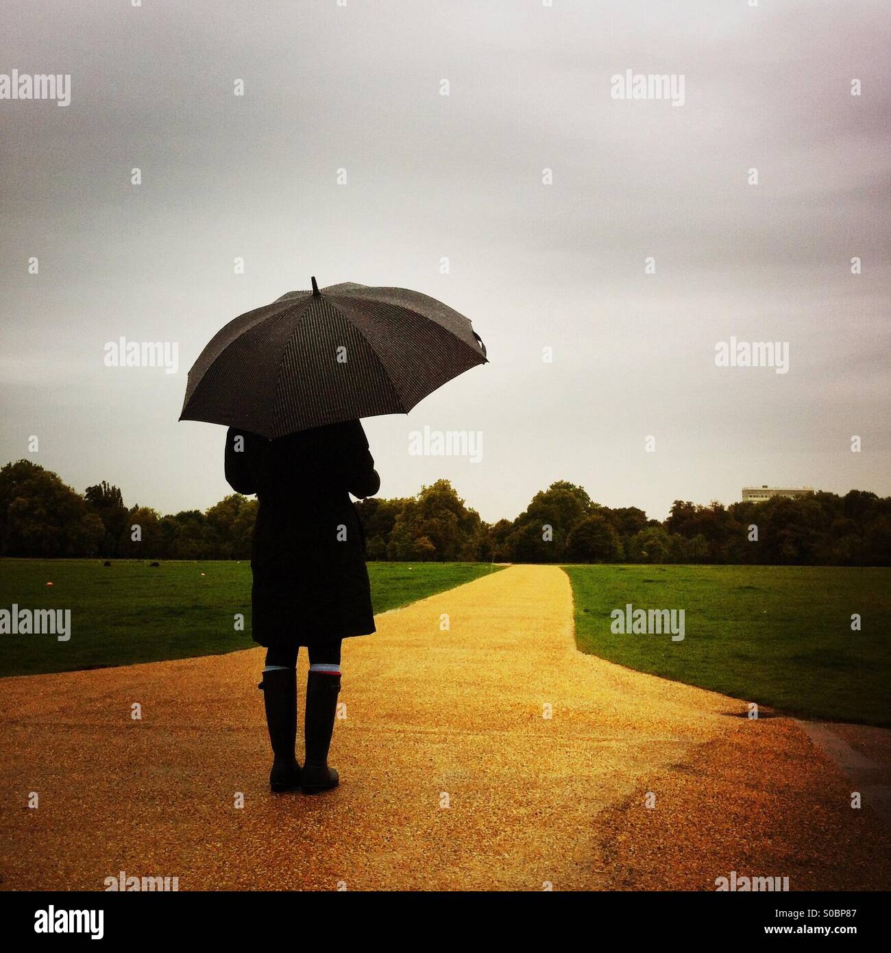 A women stands in Hyde Park on a rainy day. London, England UK. - Smartphone Captured Stock Image