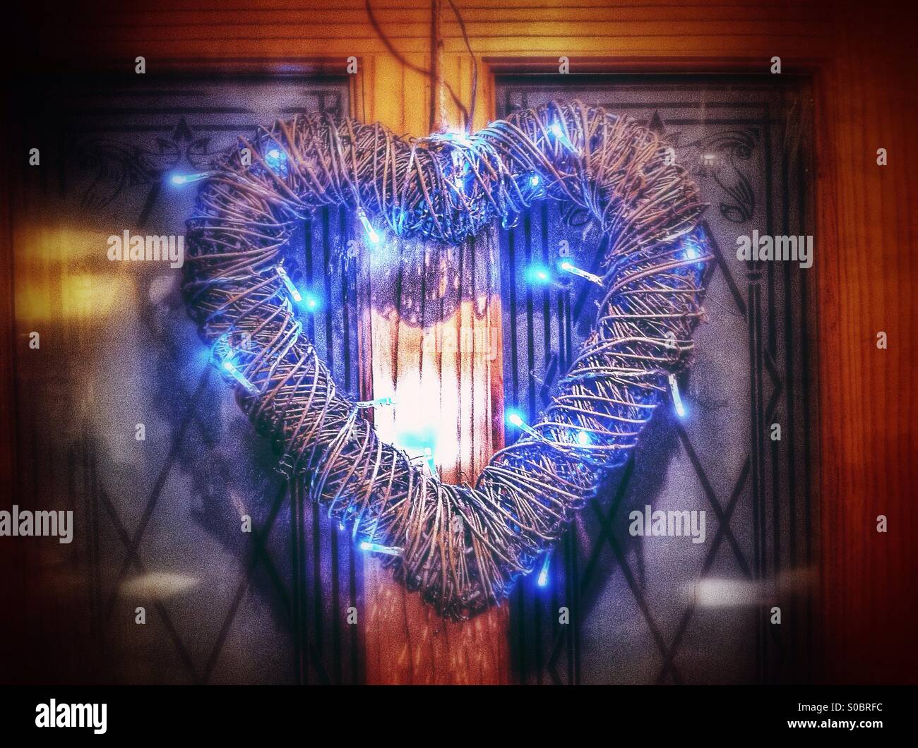 Heart shaped wreath lit with led lights. Hanging on a door. - Smartphone Captured Stock Image