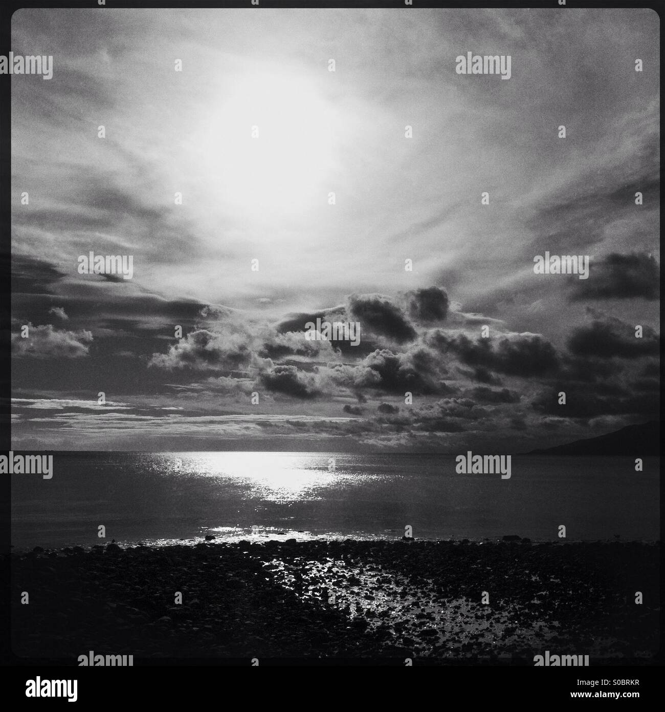 Sun in clouds and sunlight on sea and beach - Smartphone Captured Stock Image