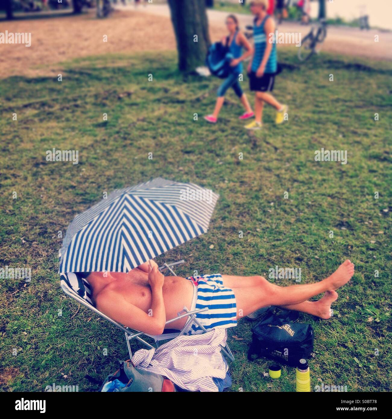 Man with umbrella on a lounger Stock Photo